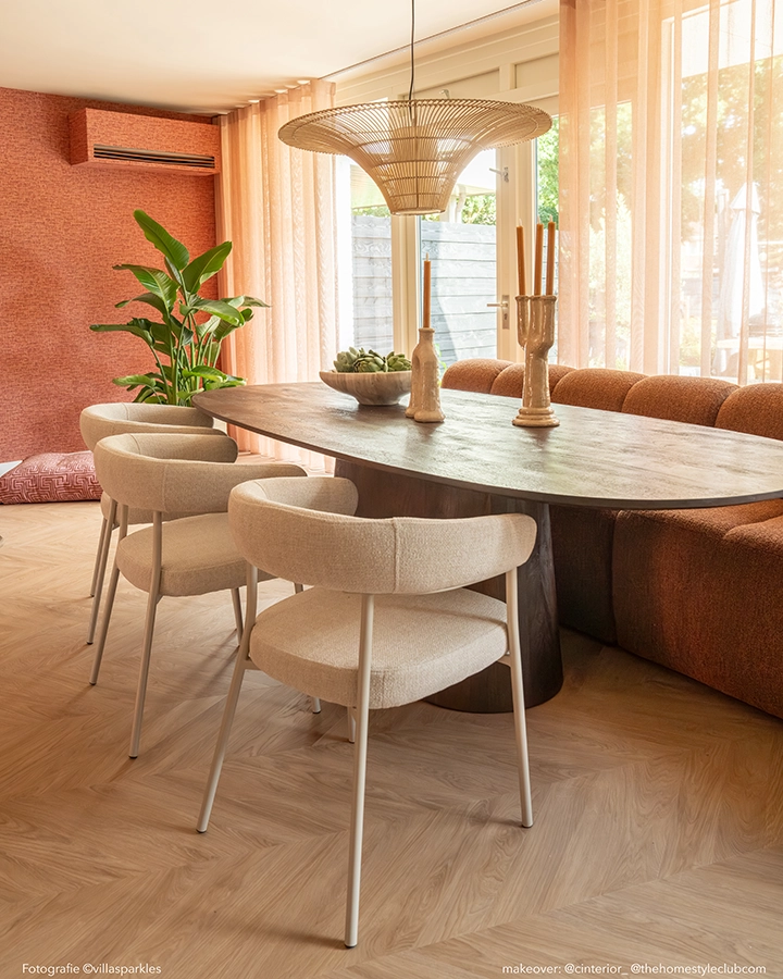 Warme eethoek met ovale donkerbruine houten eettafel, 3 beige eetkamerstoelen en een terracotta eetkamerbank.