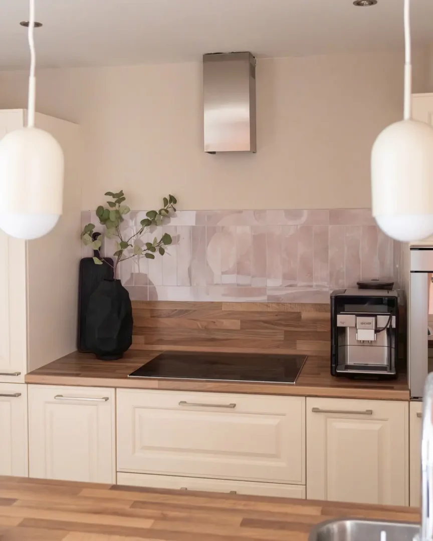 Minimalistisch houten plankje, Plancha large - black van By-Boo met een zwarte vaas Dent large - black van By-Boo en groen blad dat een frisse, serene sfeer toevoegt aan de keuken