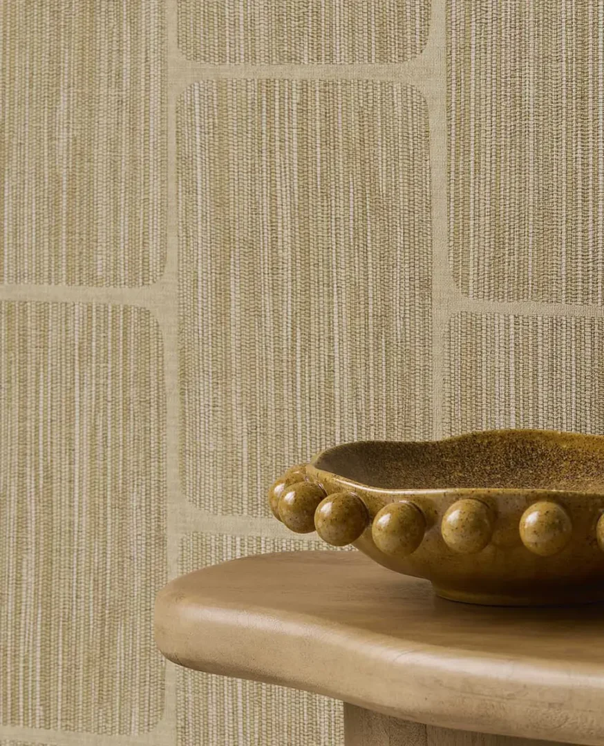 Glanzende bruine keramische schaal op een lichte houten ondergrond voor een wand met grafisch patroon.