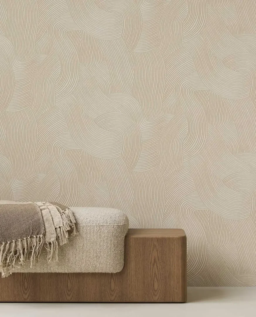 Houten bank met licht kussen en bruin‑beige plaid voor een wand met subtiel golvend patroon.