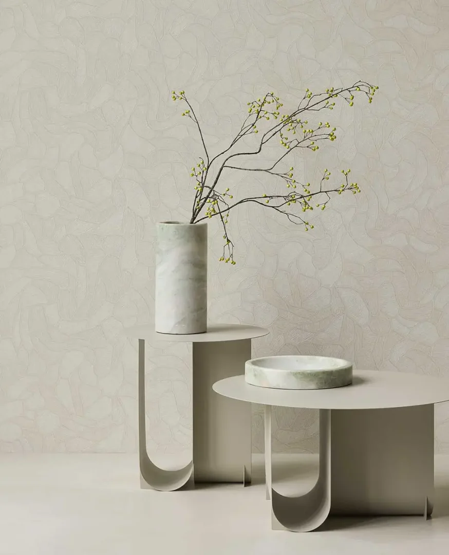 Marmeren vaas met takken en marmeren schaal op twee beige bijzettafels voor een rustige, minimalistische wand.