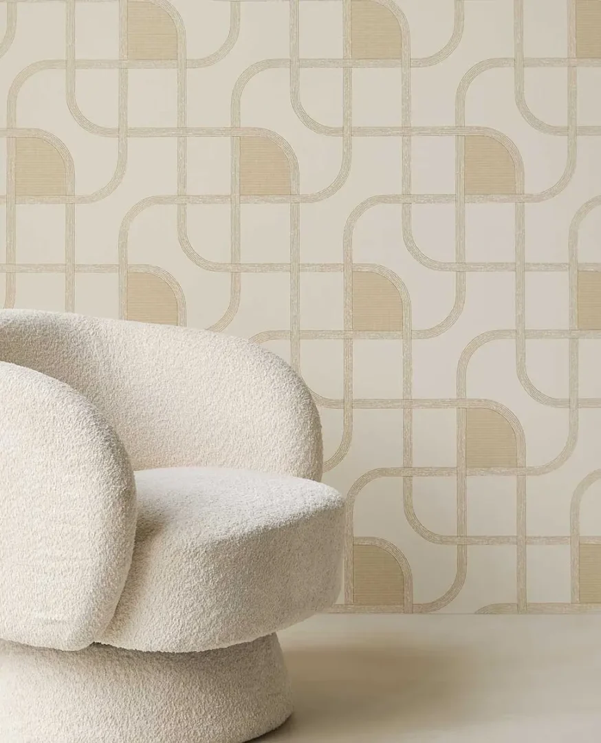 Crèmekleurige sculpturale fauteuil voor een wand met grafisch patroon in een moderne, rustige woonruimte.