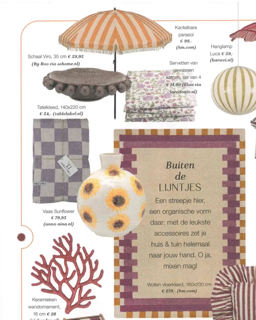 Een collage van zomerse woonaccessoires in een magazine‑layout. Te zien zijn een gestreepte parasol, keramische vazen, een hanglamp, servetten met bloemenprint, een schaal met bolvormige rand, een geruit tafelkleed en een wollen vloerkleed in oker‑ en paars‑tinten. In het midden staat de tekst “Buiten de lijntjes”, die uitnodigt om strepen en organische vormen speels te combineren voor huis en tuin.